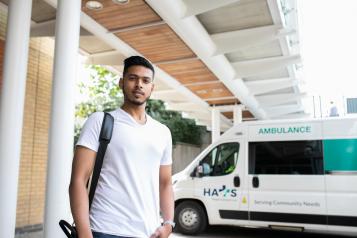 A young black man standing in front of an ambulance